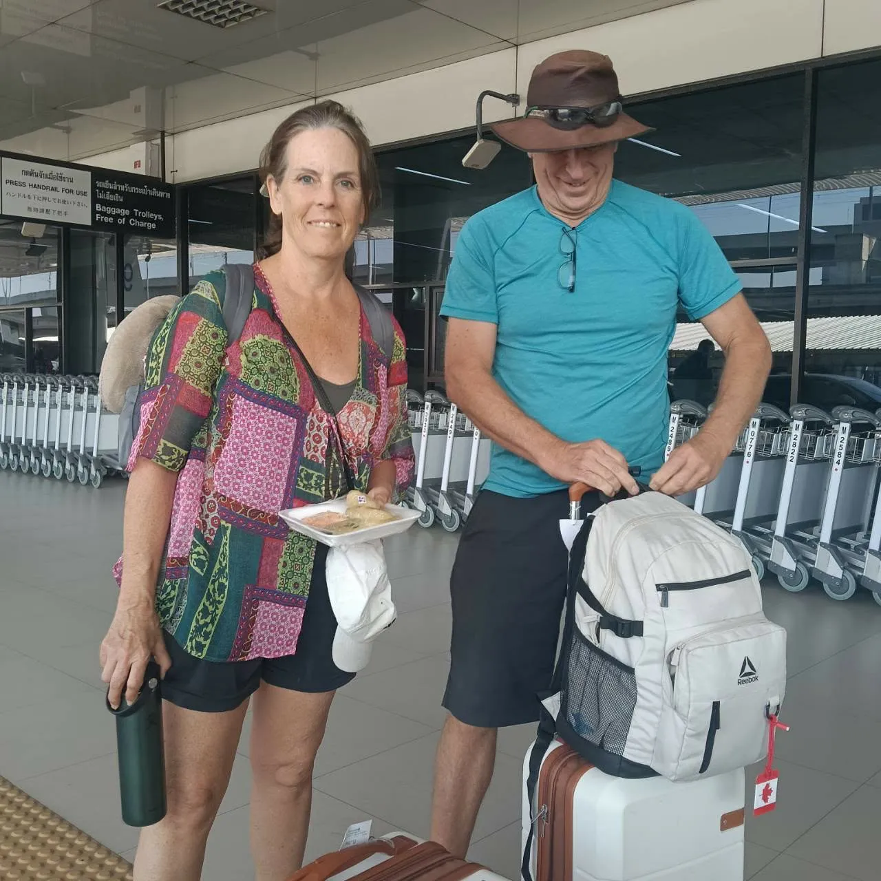 A couple with their luggage at the airport before the transfer to Kanchanaburi